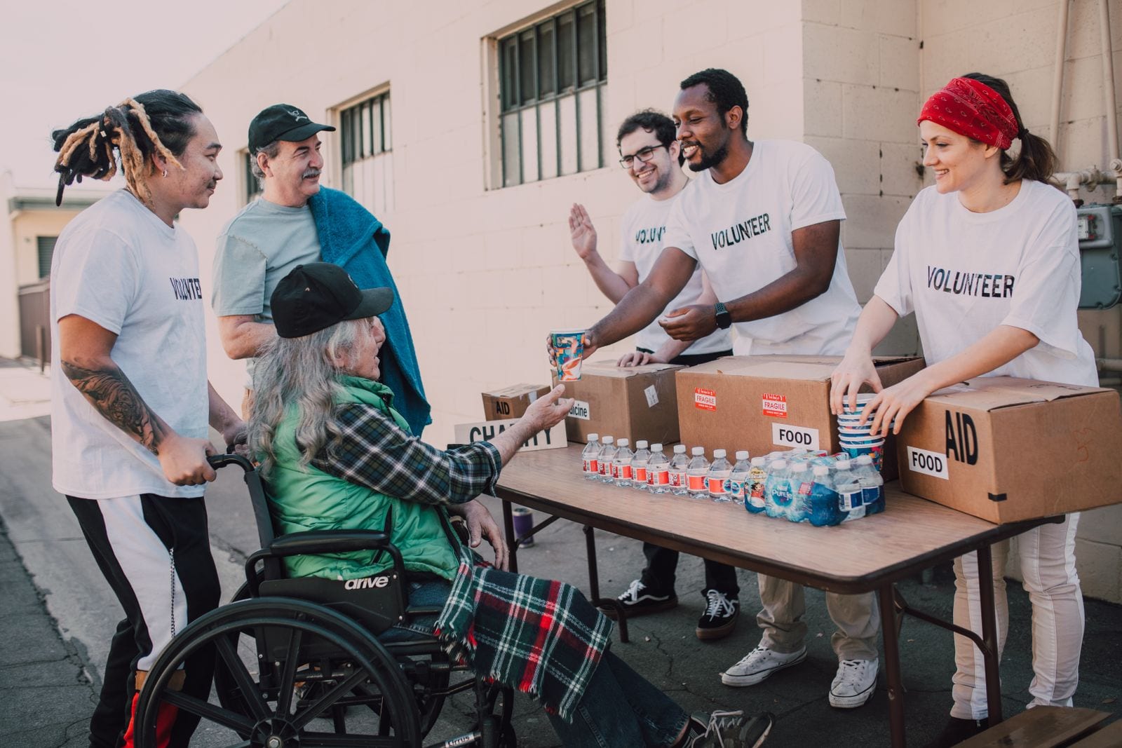 Volunteers in matching shirts handing out food and water at a community aid table
