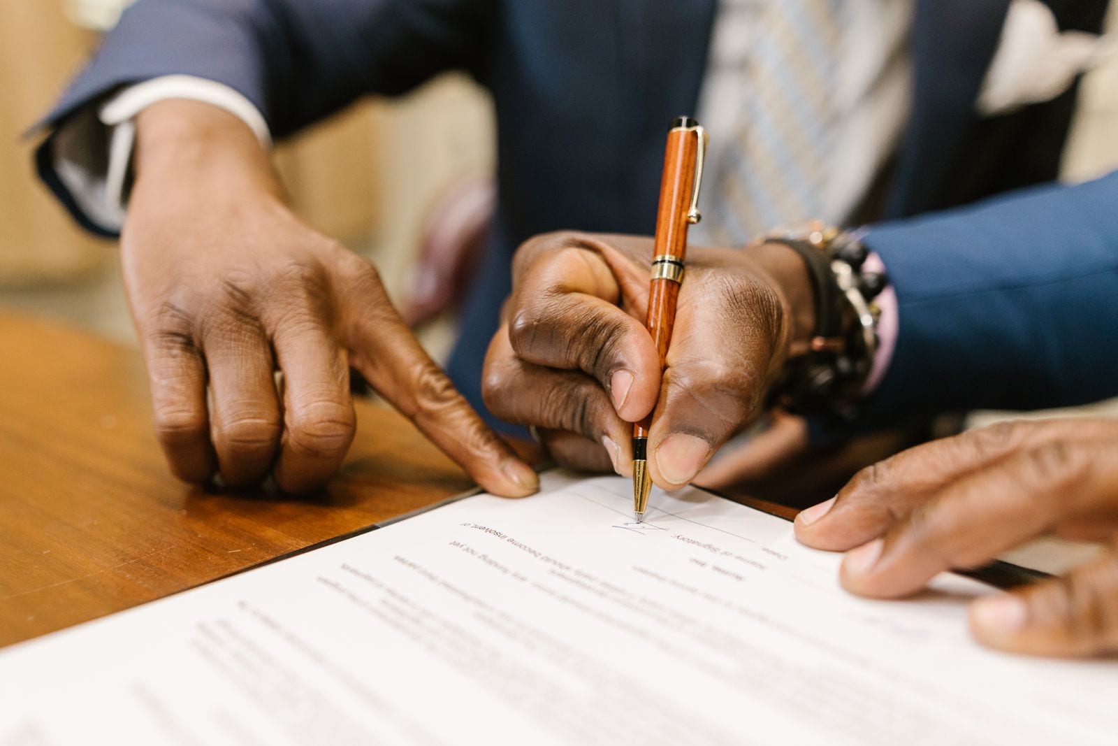 Close-up of two people at a desk working through a printed document with a pen